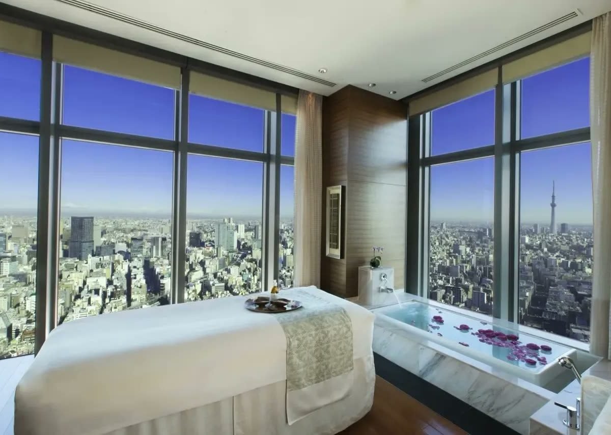 Spa treatment room with floor-to-ceiling city views and a marble bath