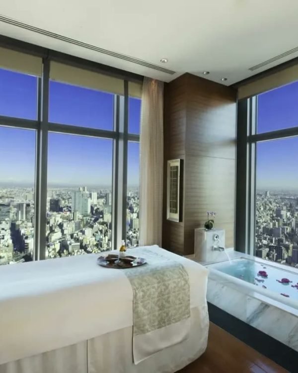 Spa treatment room with floor-to-ceiling city views and a marble bath