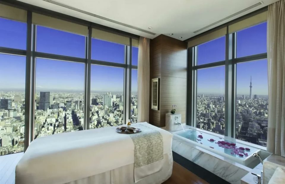 Spa treatment room with floor-to-ceiling city views and a marble bath