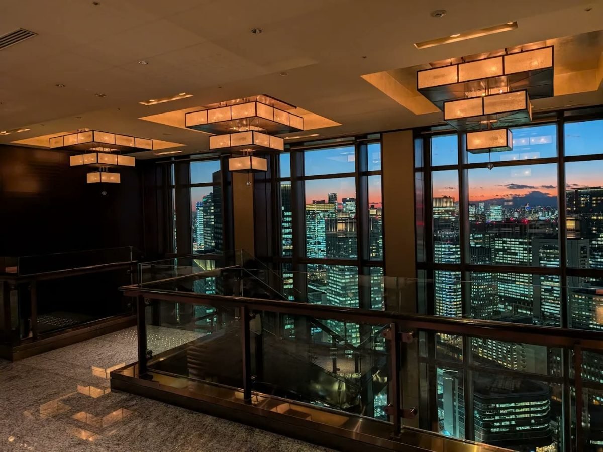 Hotel bar at dusk with skyline views through floor-to-ceiling glass