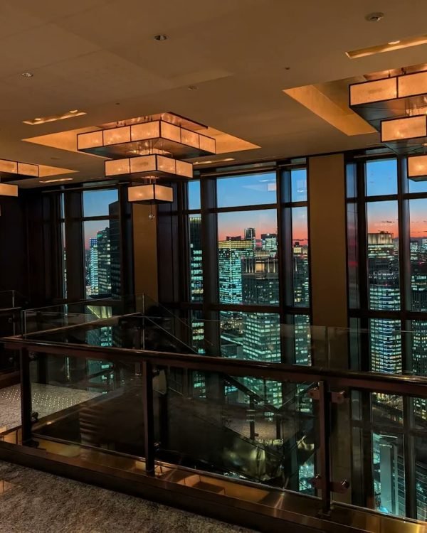 Hotel bar at dusk with skyline views through floor-to-ceiling glass