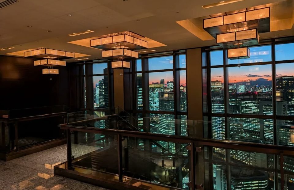 Hotel bar at dusk with skyline views through floor-to-ceiling glass