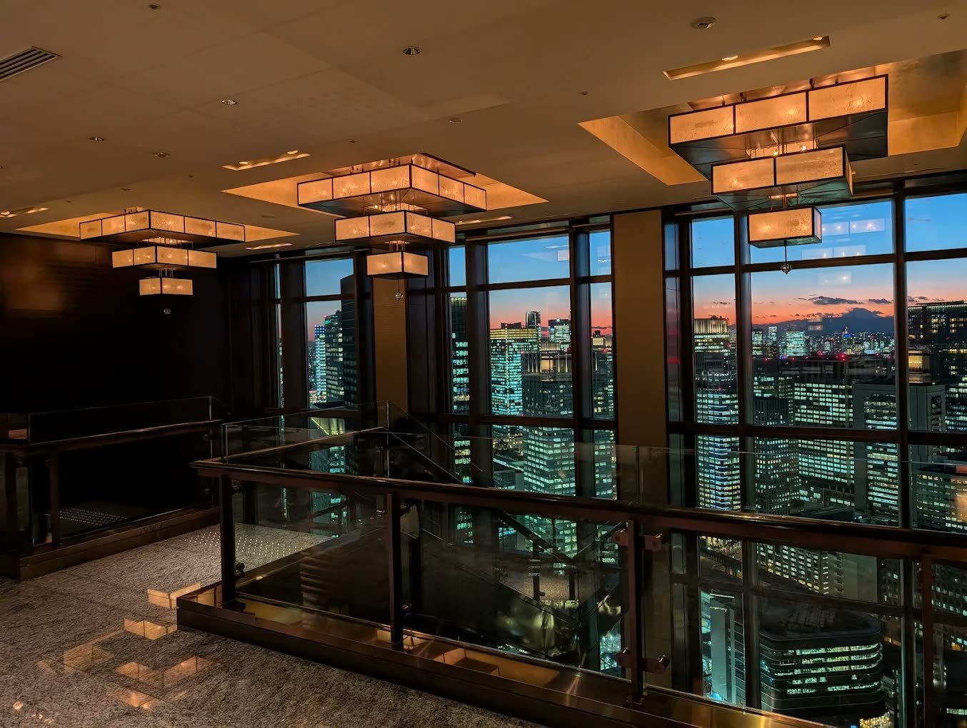 Hotel bar at dusk with skyline views through floor-to-ceiling glass
