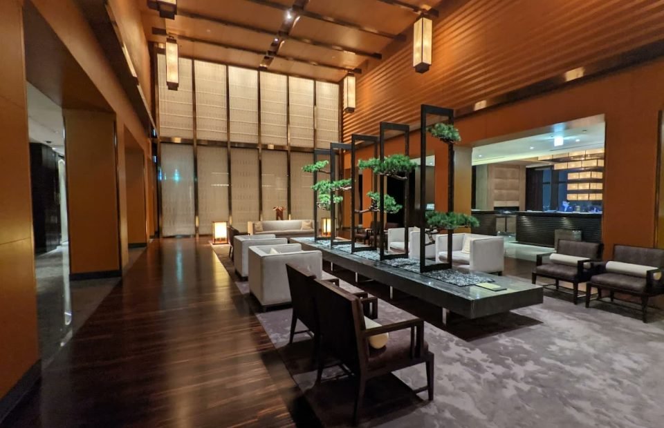 Double-height lounge with timber screens, lanterns and bonsai