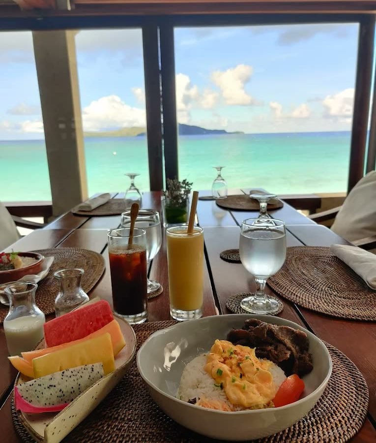 Breakfast laid on a shaded veranda with a sea view