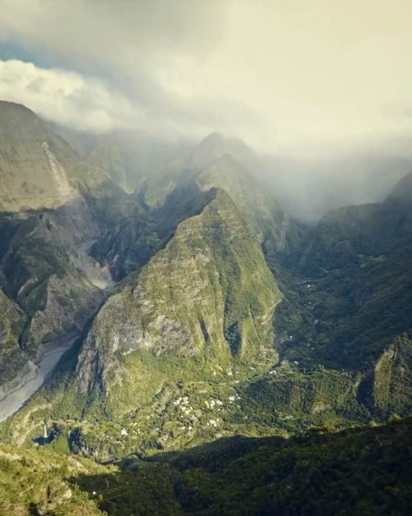 Steep green mountain valley under drifting cloud