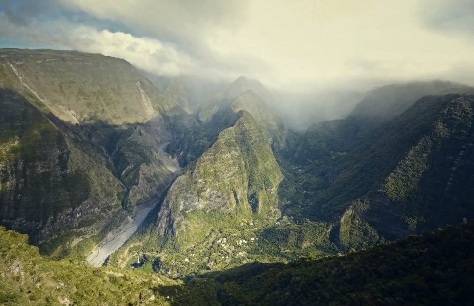 Steep green mountain valley under drifting cloud