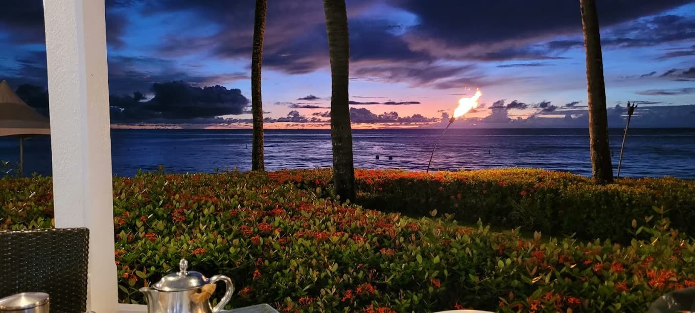 Sunset over the Caribbean Sea framed by palms from a terrace at Fairmont Royal Pavilion, Barbados