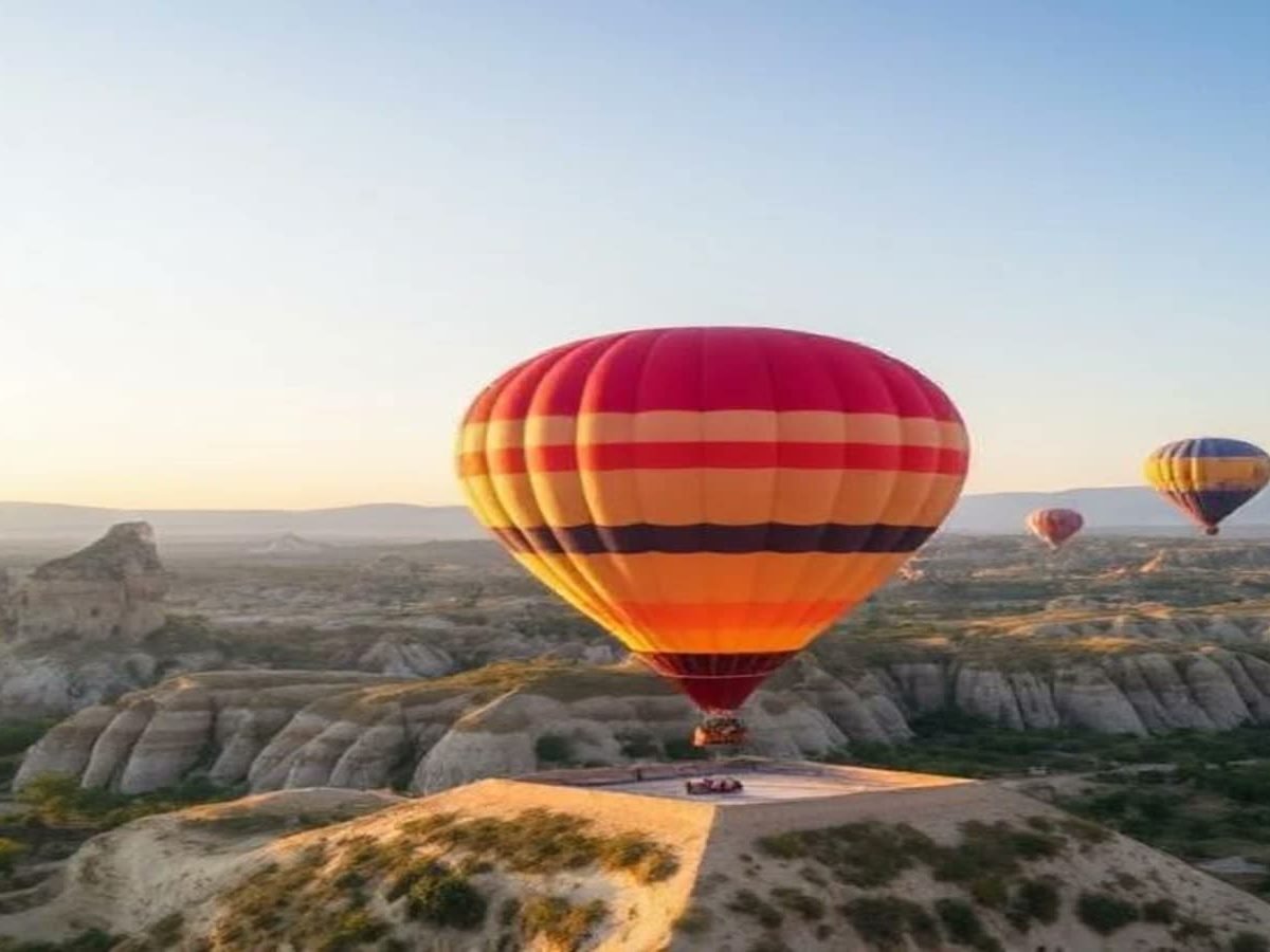 Hot air balloon drifting over rock formations at sunrise in Cappadocia