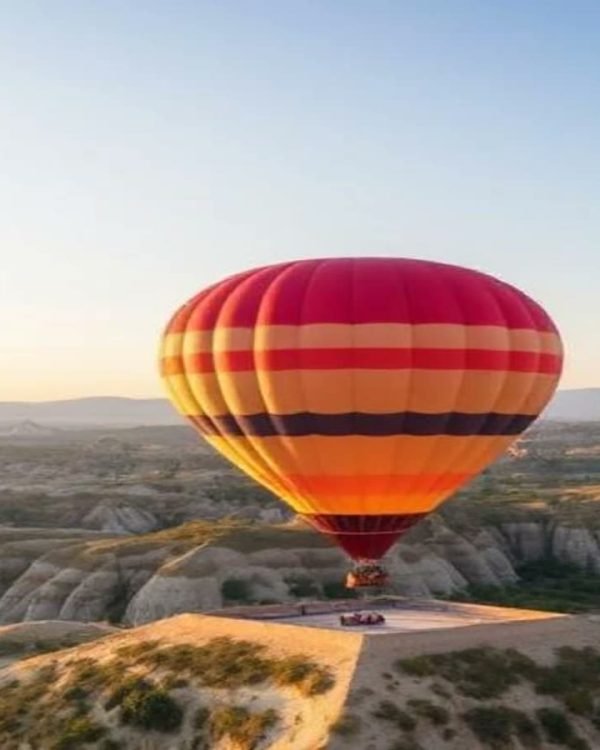 Hot air balloon drifting over rock formations at sunrise in Cappadocia
