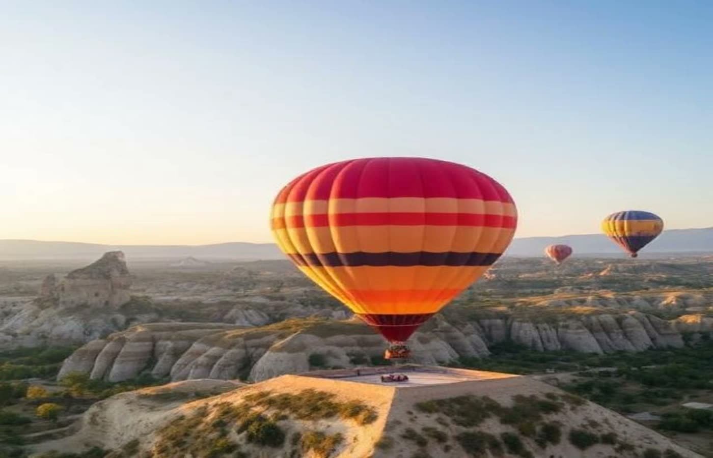 Hot air balloon drifting over rock formations at sunrise in Cappadocia
