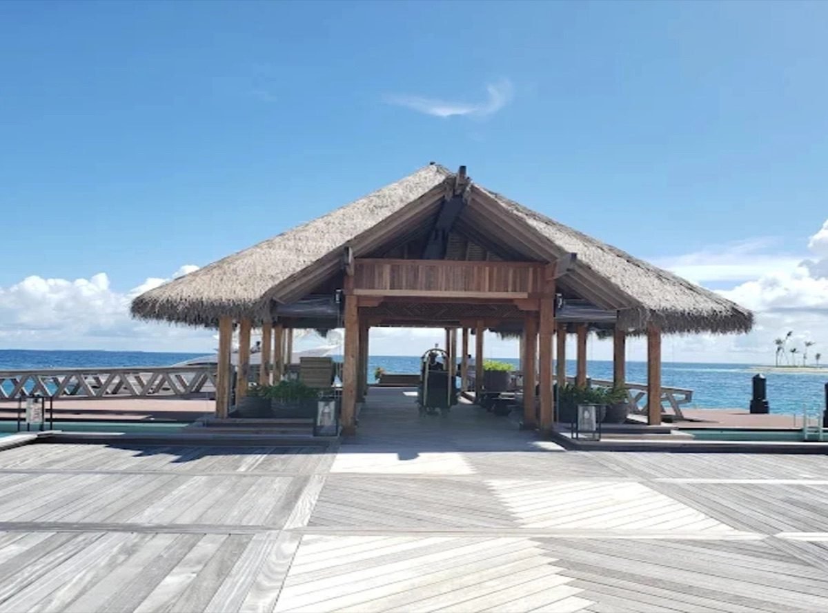Thatched overwater arrival pavilion on a timber jetty in the Maldives