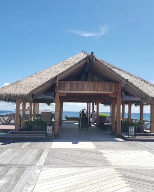Thatched overwater arrival pavilion on a timber jetty in the Maldives