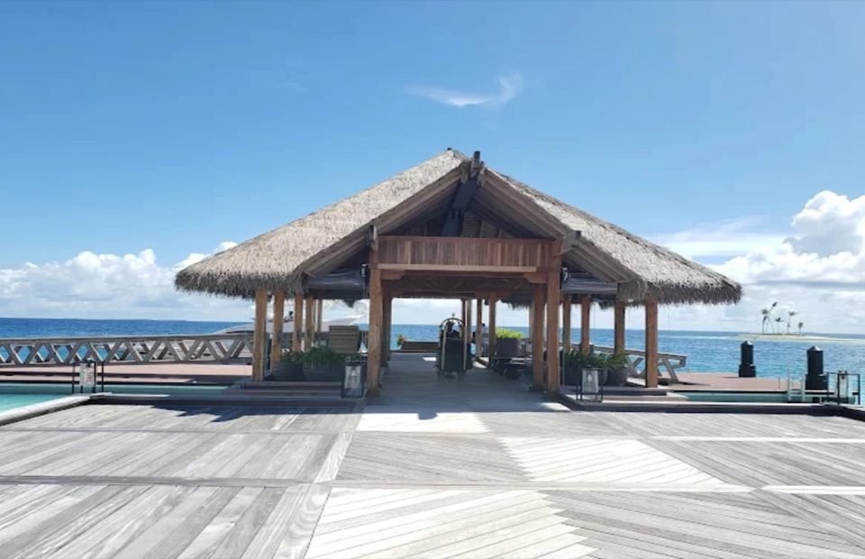 Thatched overwater arrival pavilion on a timber jetty in the Maldives