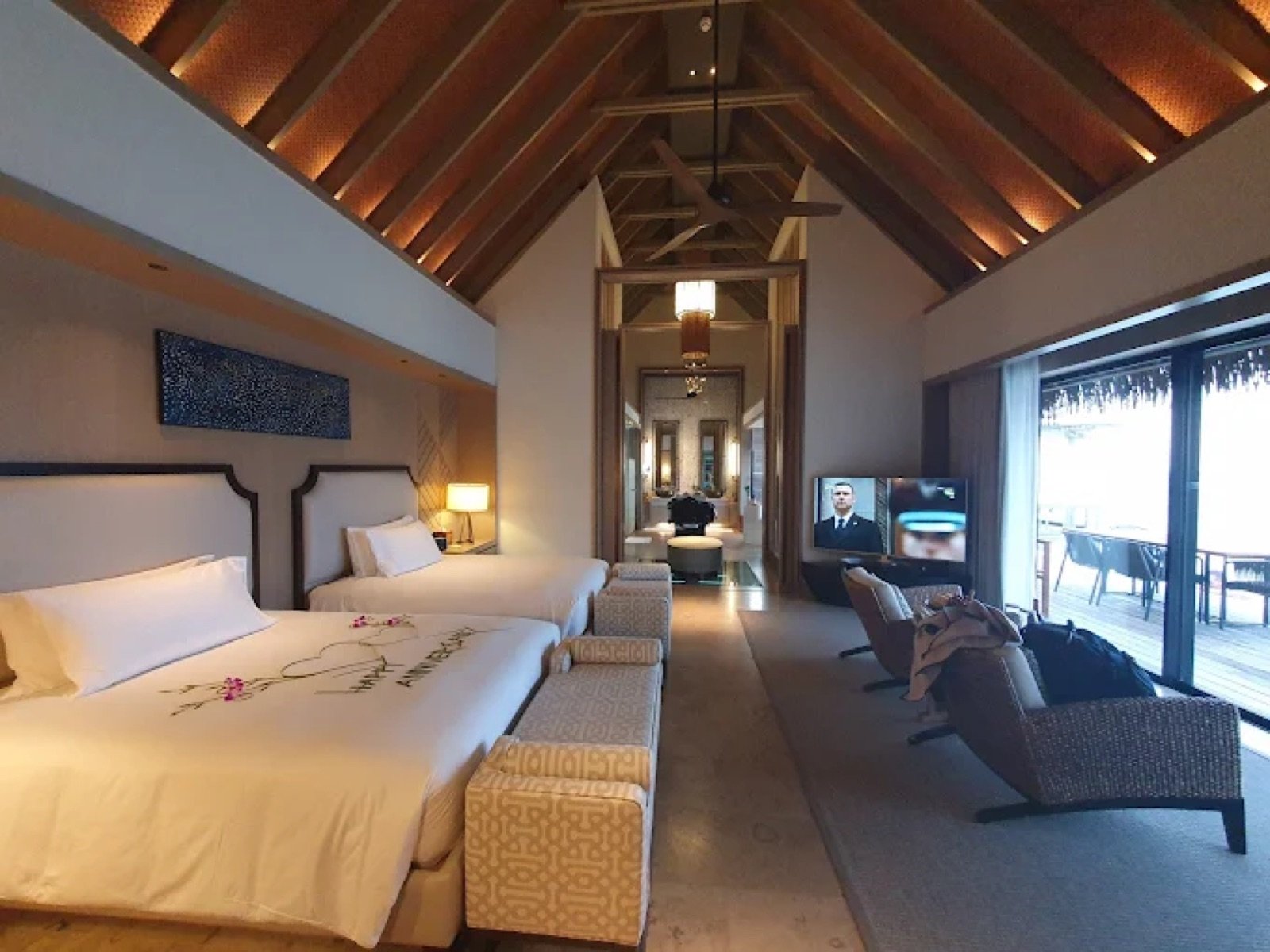 Vaulted timber ceiling and twin beds inside a Maldives overwater villa