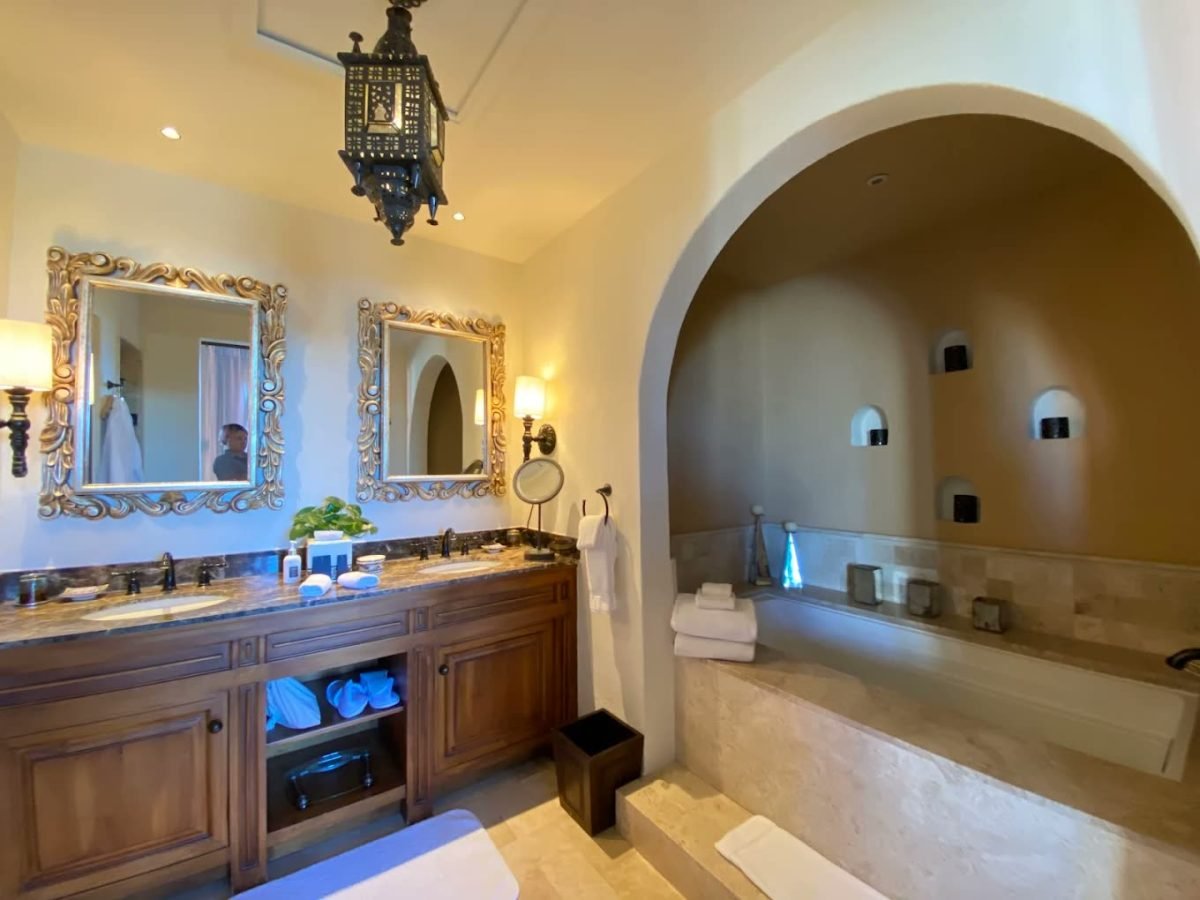 Suite bathroom with an arched stone alcove tub and double vanity