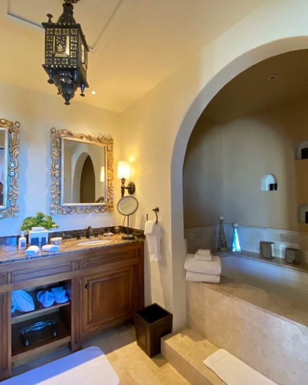 Suite bathroom with an arched stone alcove tub and double vanity