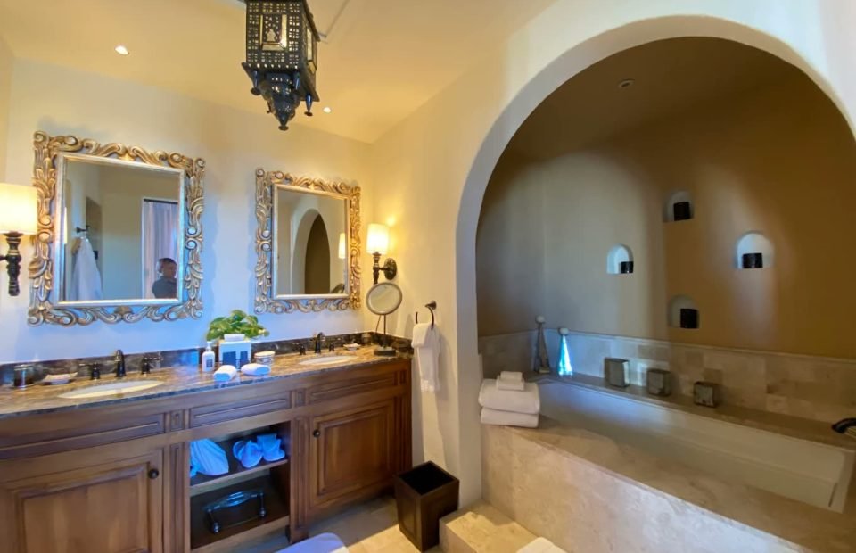 Suite bathroom with an arched stone alcove tub and double vanity
