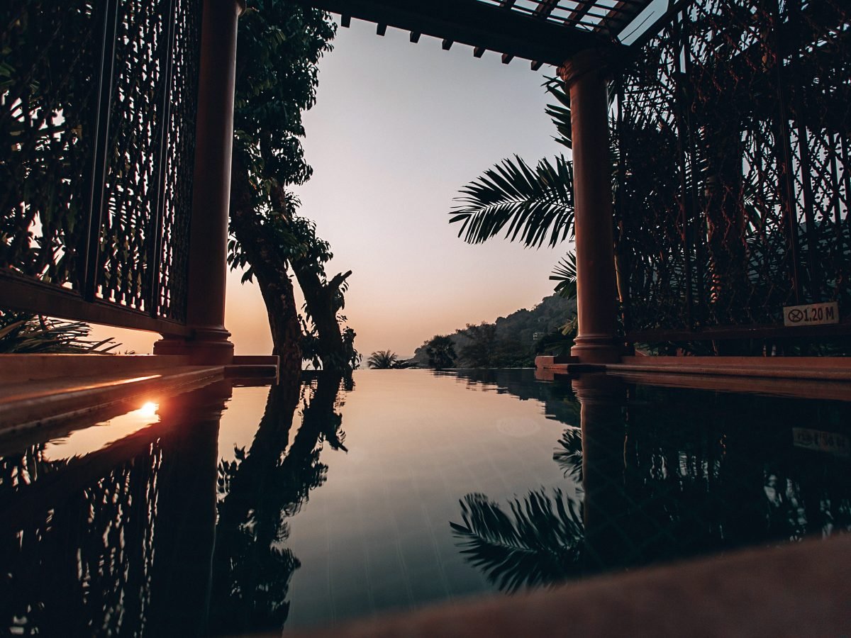 Timber pavilion framing an infinity pool at sunset