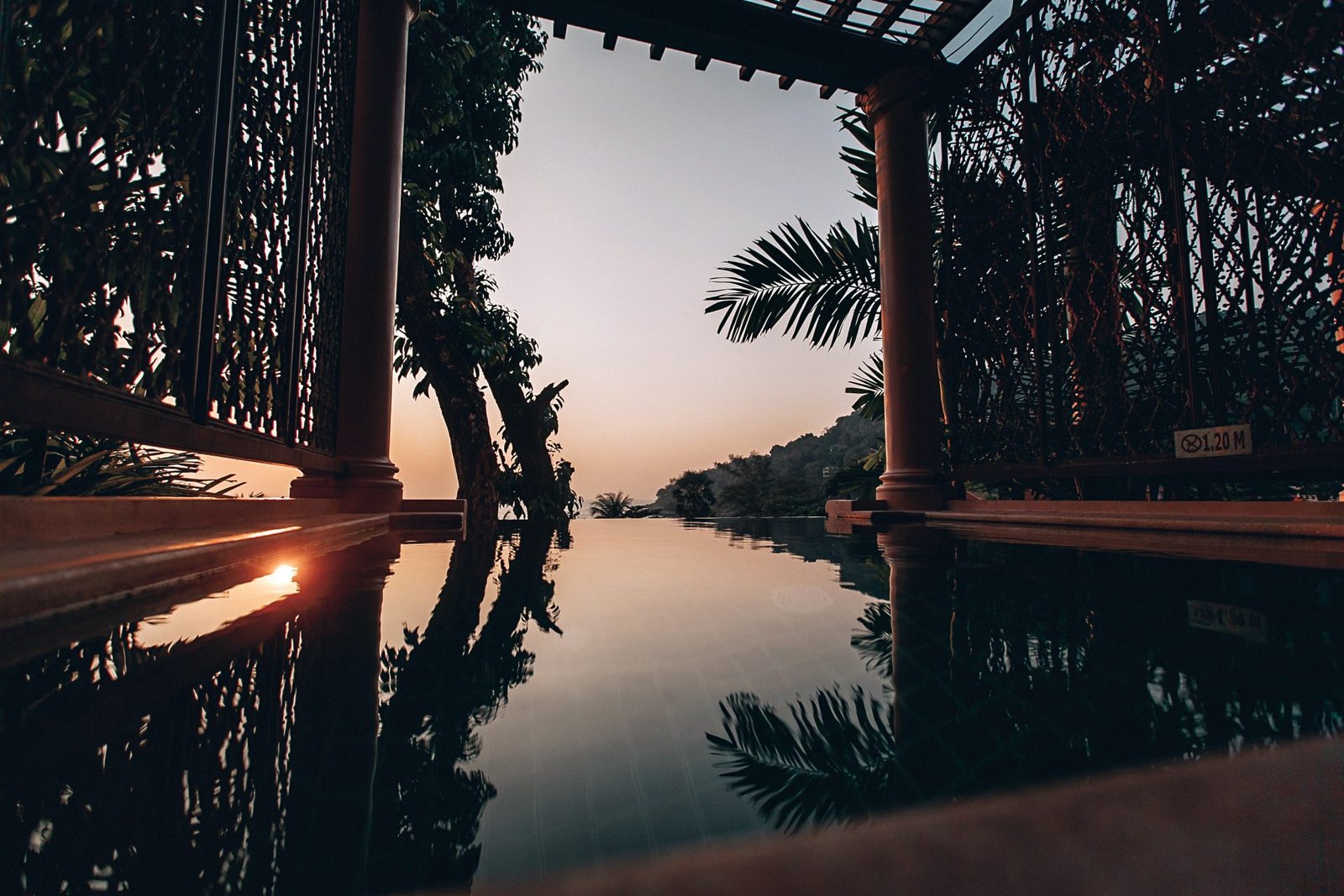 Timber pavilion framing an infinity pool at sunset