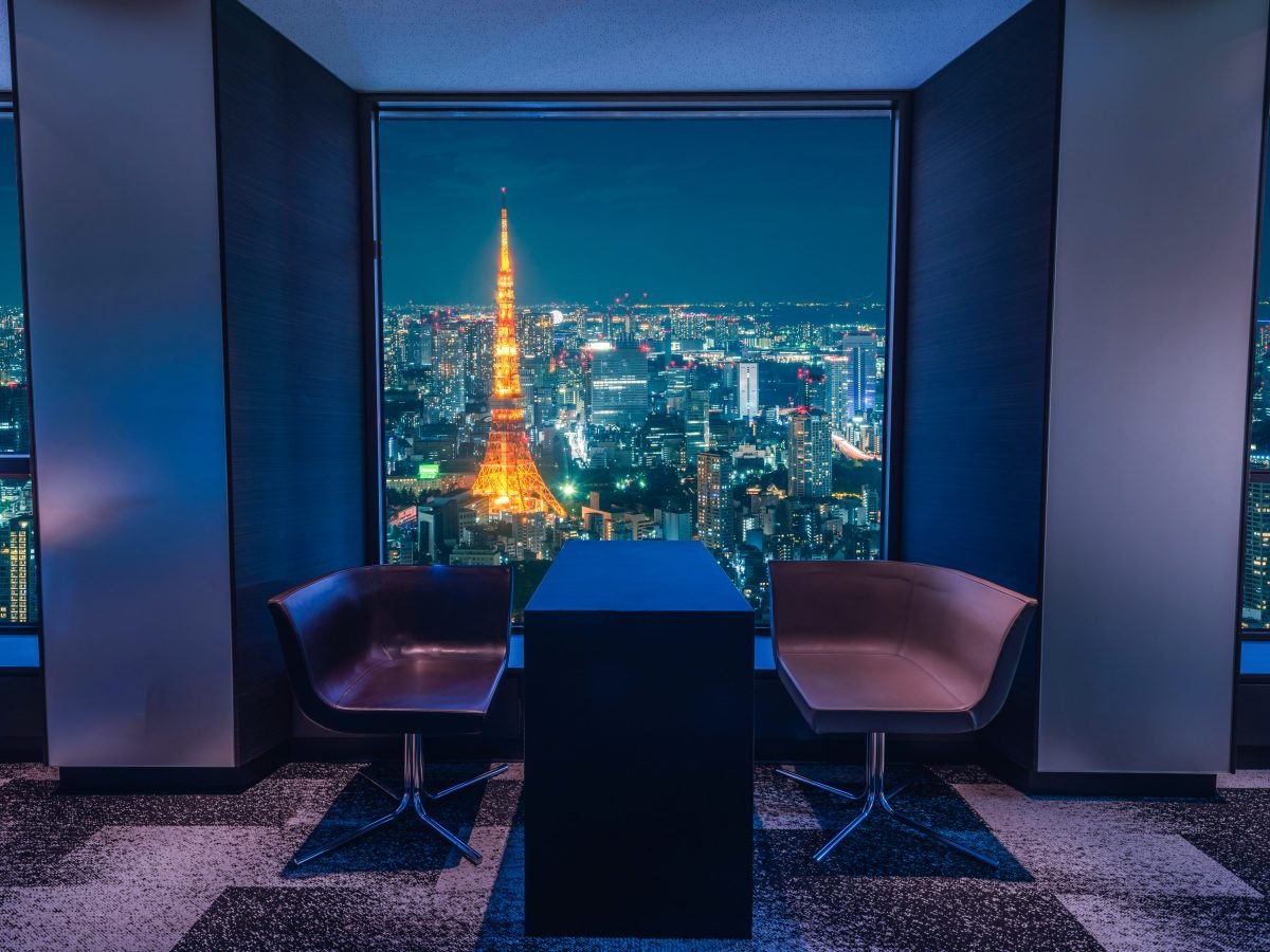 Warm-lit hotel lounge framing Tokyo Tower at night