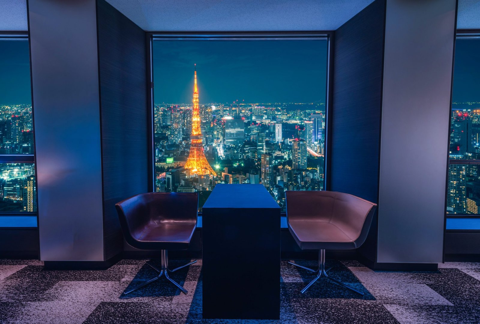 Warm-lit hotel lounge framing Tokyo Tower at night