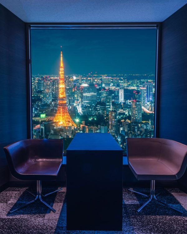 Warm-lit hotel lounge framing Tokyo Tower at night