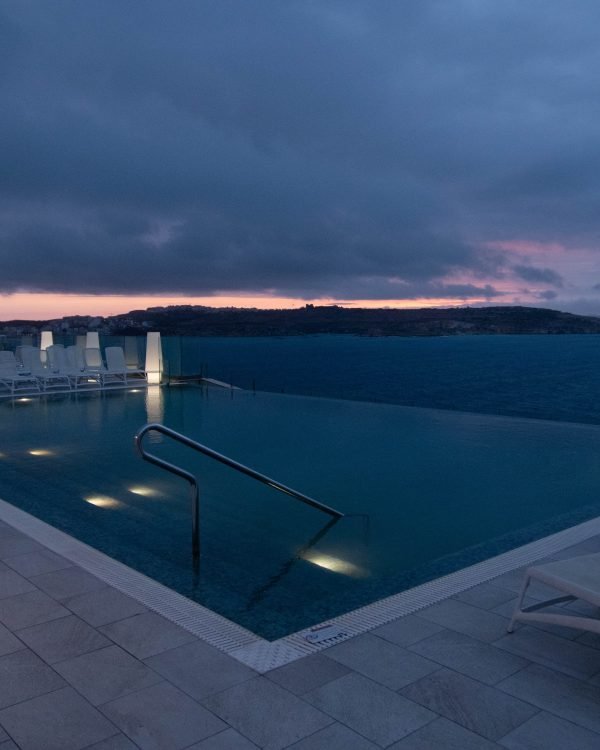 Rooftop infinity pool with lit canopy at blue dusk