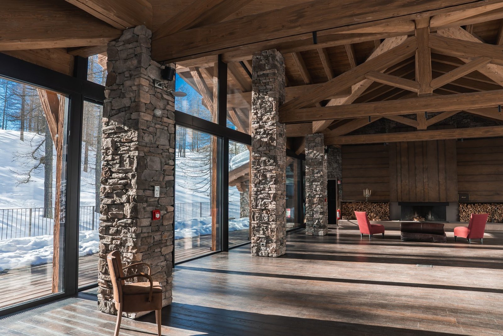 Rustic alpine chalet lounge with stone columns, fire and mountain view
