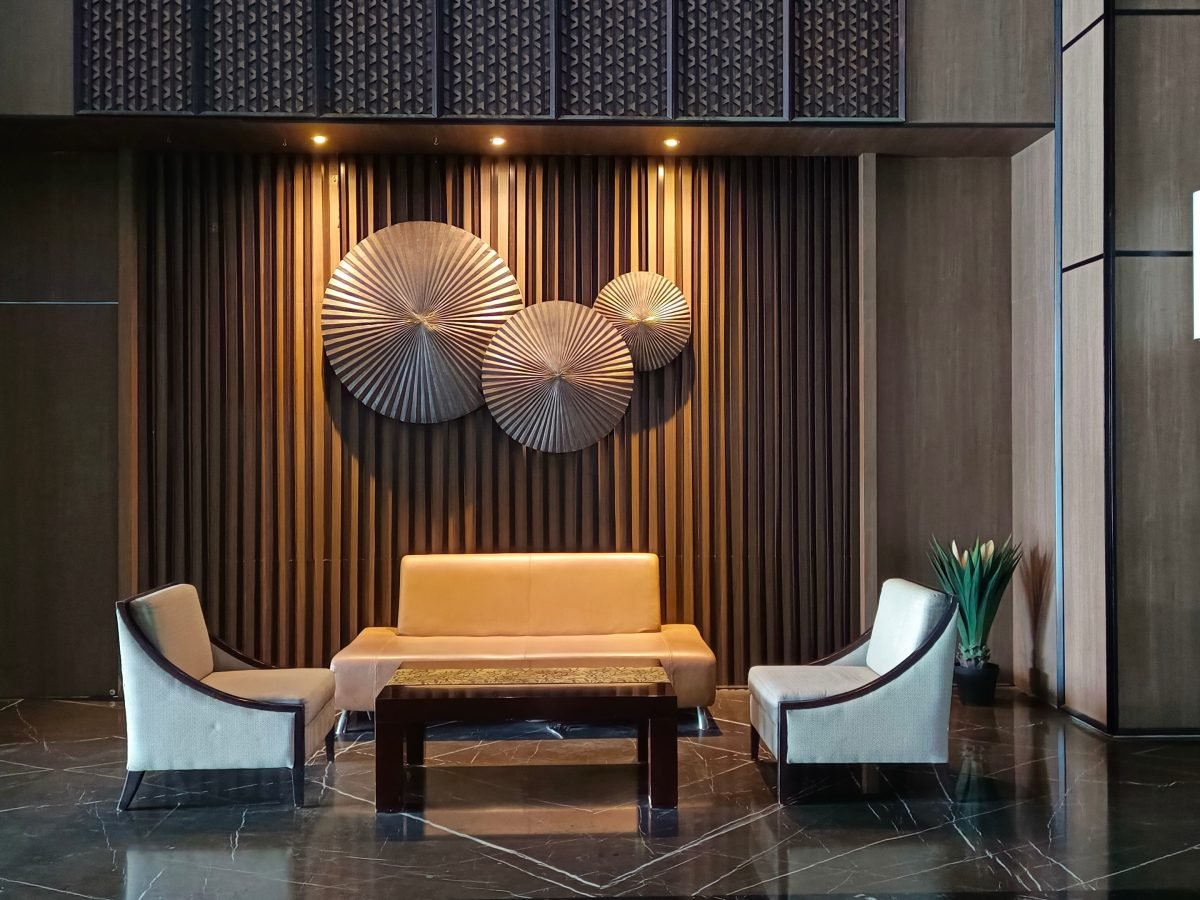 Dark hotel lounge with a gold slatted wall and brass discs