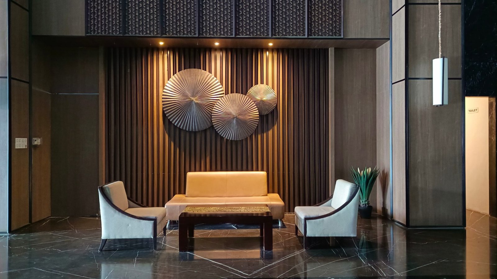 Dark hotel lounge with a gold slatted wall and brass discs