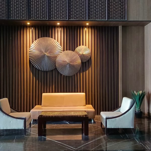Dark hotel lounge with a gold slatted wall and brass discs