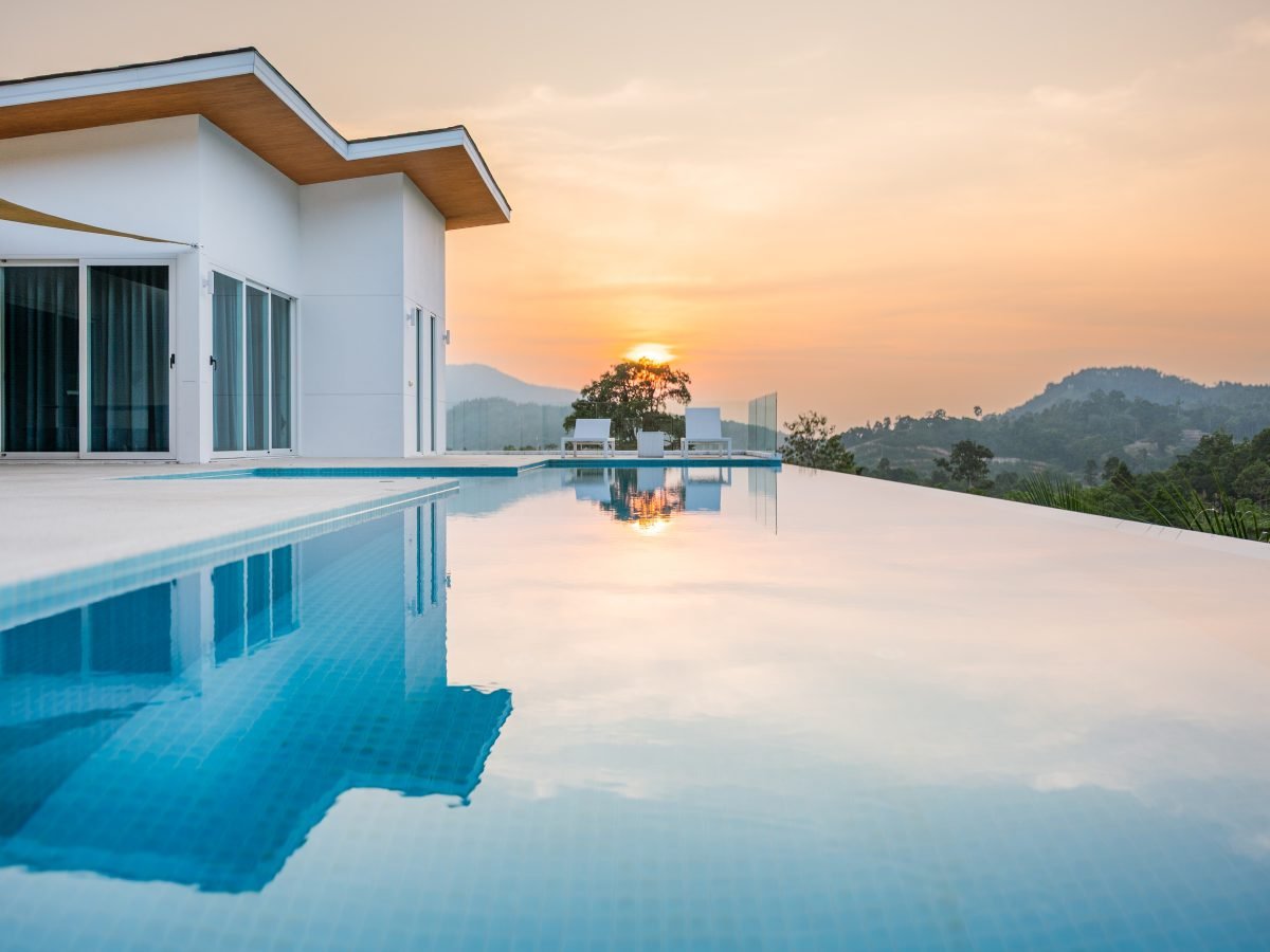 Modern villa mirrored in a still infinity pool at sunset
