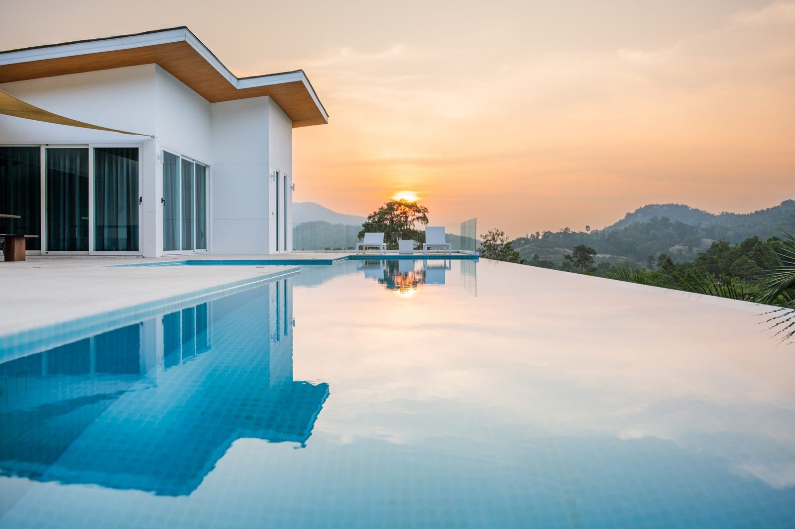 Modern villa mirrored in a still infinity pool at sunset