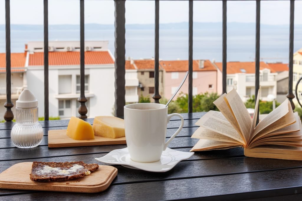 Coffee and a book on a balcony over terracotta rooftops