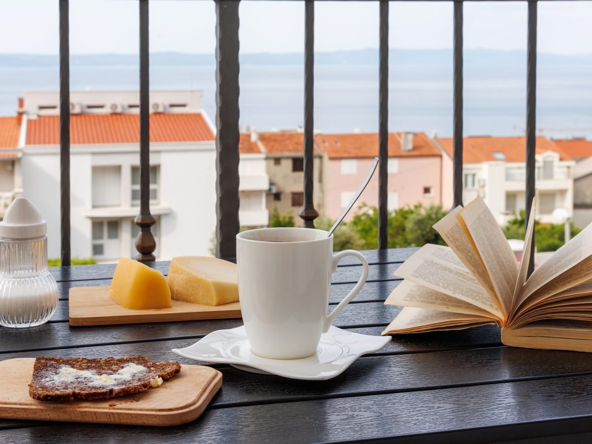 Coffee and a book on a balcony over terracotta rooftops