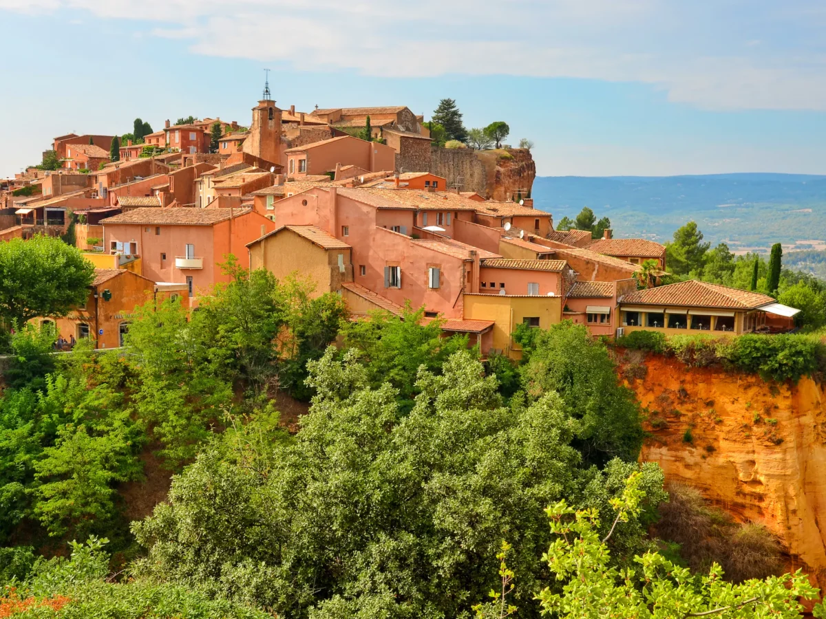 Panoramic view of Roussillon village in Provence, France, with colourful ochre buildings and dramatic cliffs