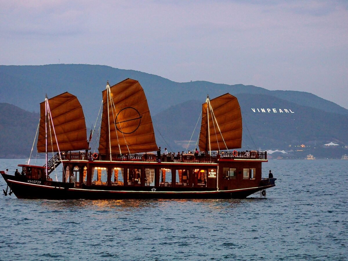 Emperor Cruises luxury wooden boat with traditional red sails cruising across calm water near Vinpearl in Vietnam.